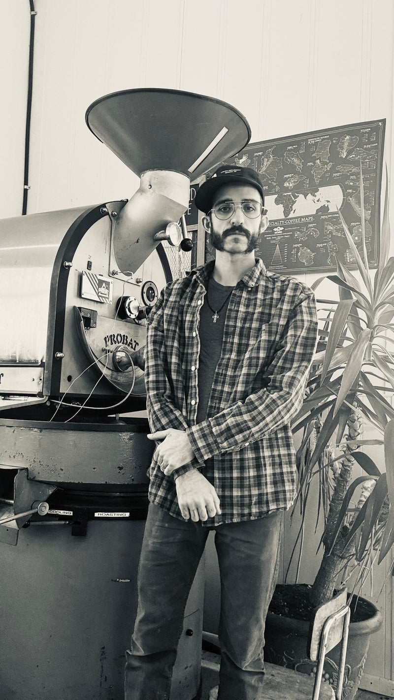 Devin Thunhorst standing beside the Probat coffee roaster at Lake Wind Coffee in Port Wing, Wisconsin.